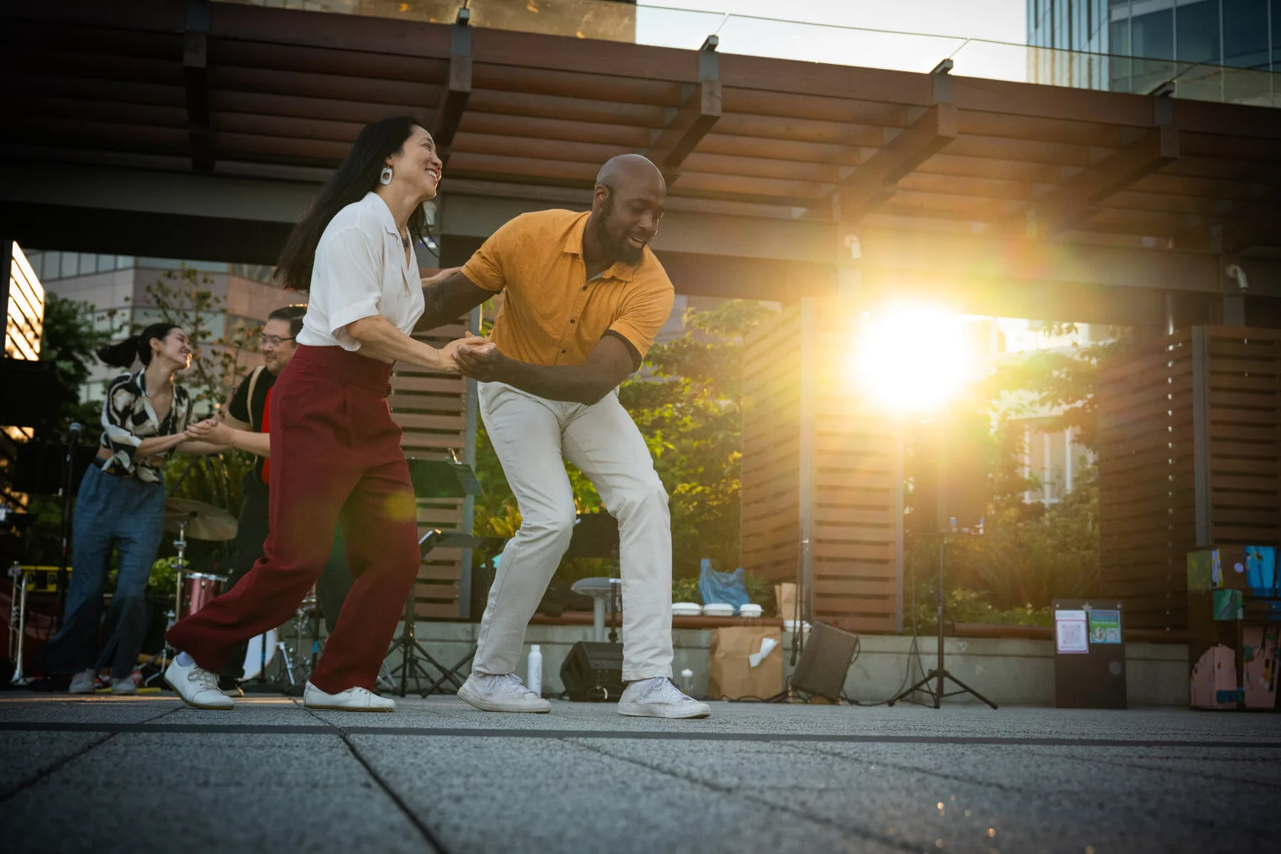 Two dancers laughing mid dance as the sun sets behind the stage at the 2026 Bellevue City Hall event.