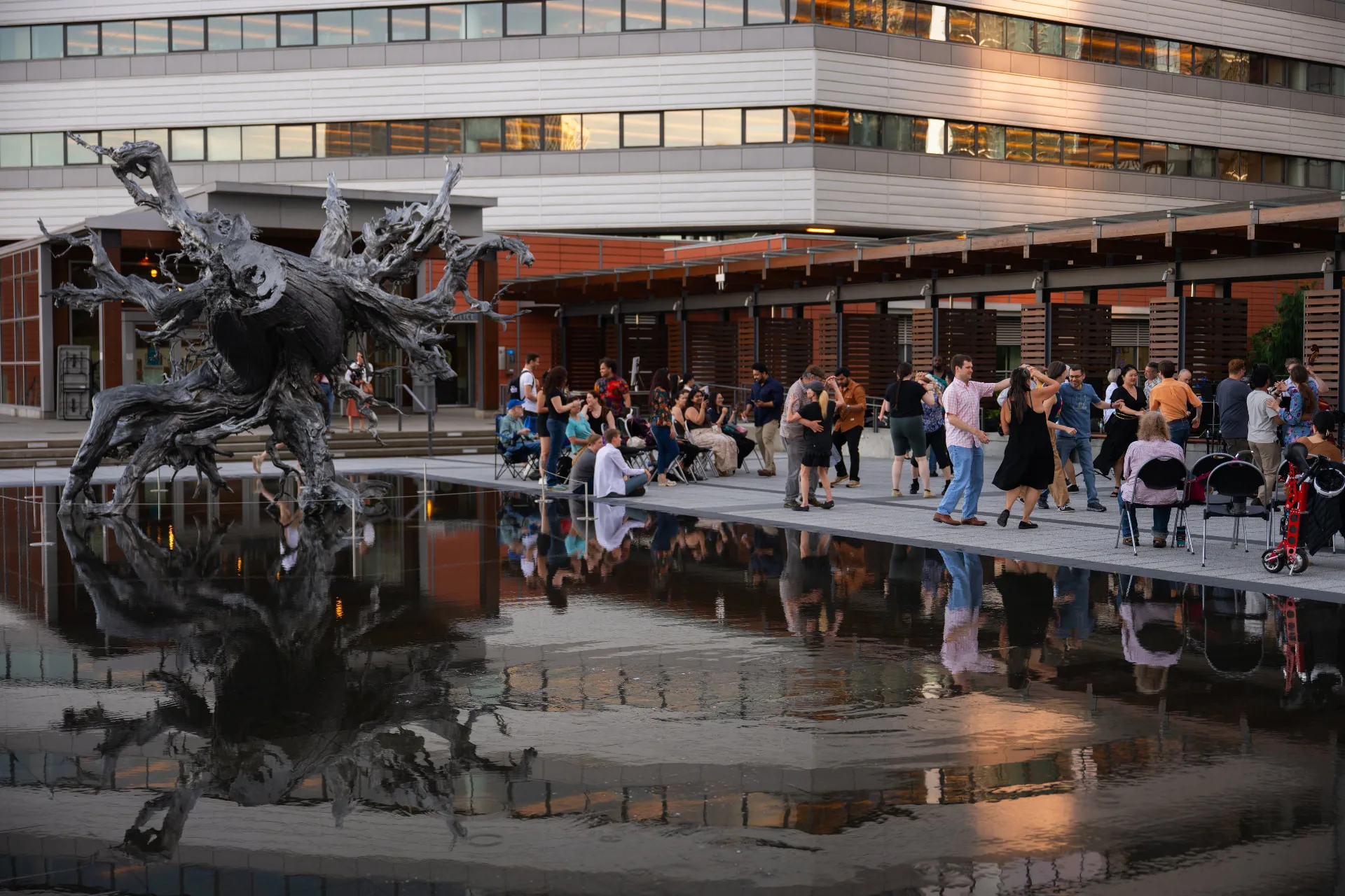 Dancers and onlookers on the plaza at Bellevue City Hall, the reflecting pool in the foreground, at the free July 2025 event.